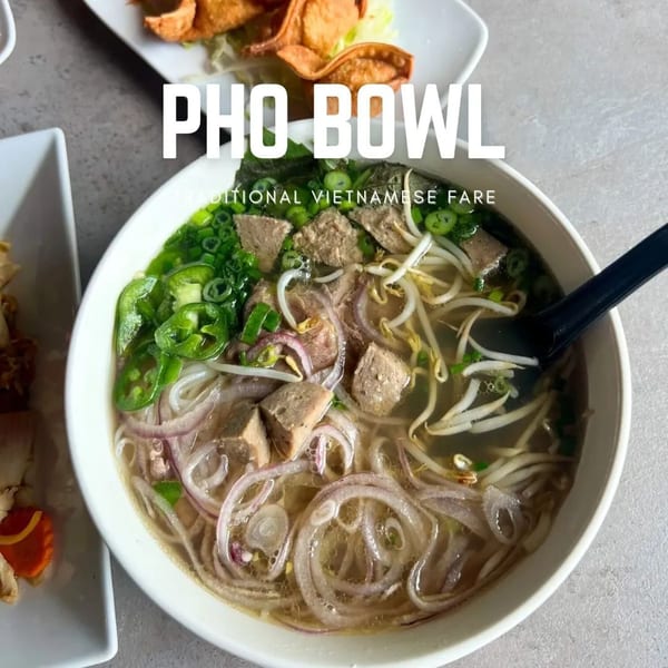 A close-up of a Pho Bowl with noodles, meat, bean sprouts, onions, and green herbs.